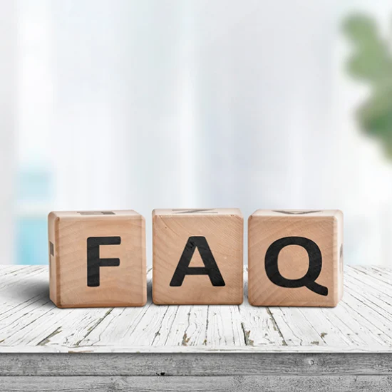 Wooden blocks on a white table spell "FAQ" in bold black letters, set against a blurred background with a calm and informative tone.