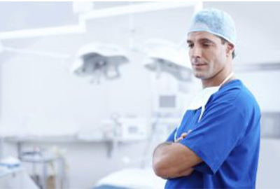 Male surgeon in scrubs stands in a dental operating room.
